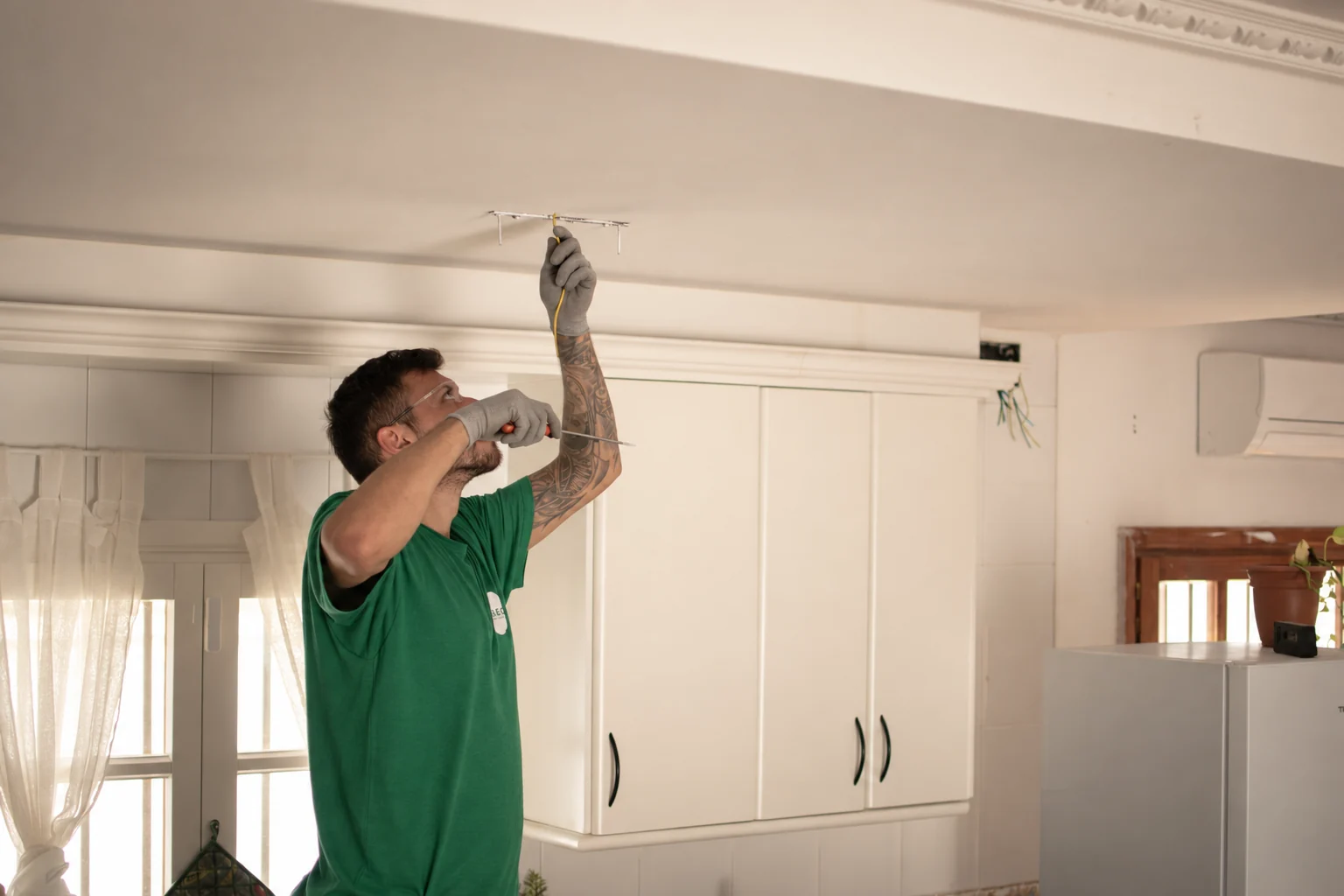 A member of the A.BEC team working with tools and wiring in the ceiling of a home.